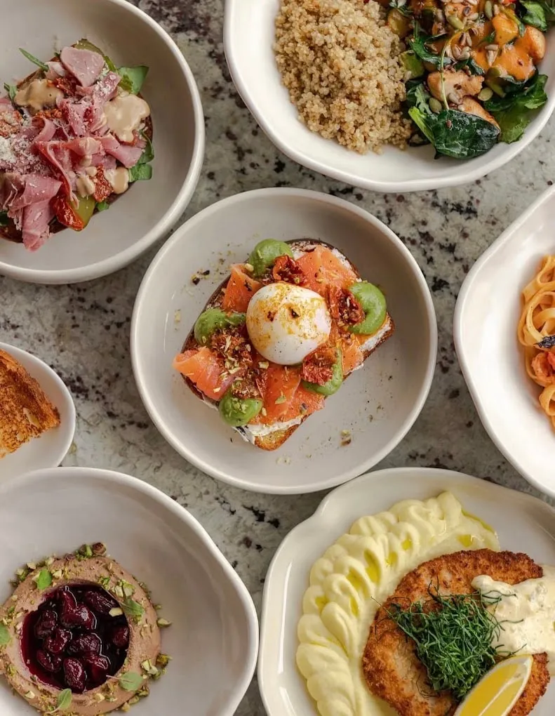 A lunch table: salmon toast with burrata, a quinoa bowl, pâté with cherries, schnitzel with mashed potato and pasta